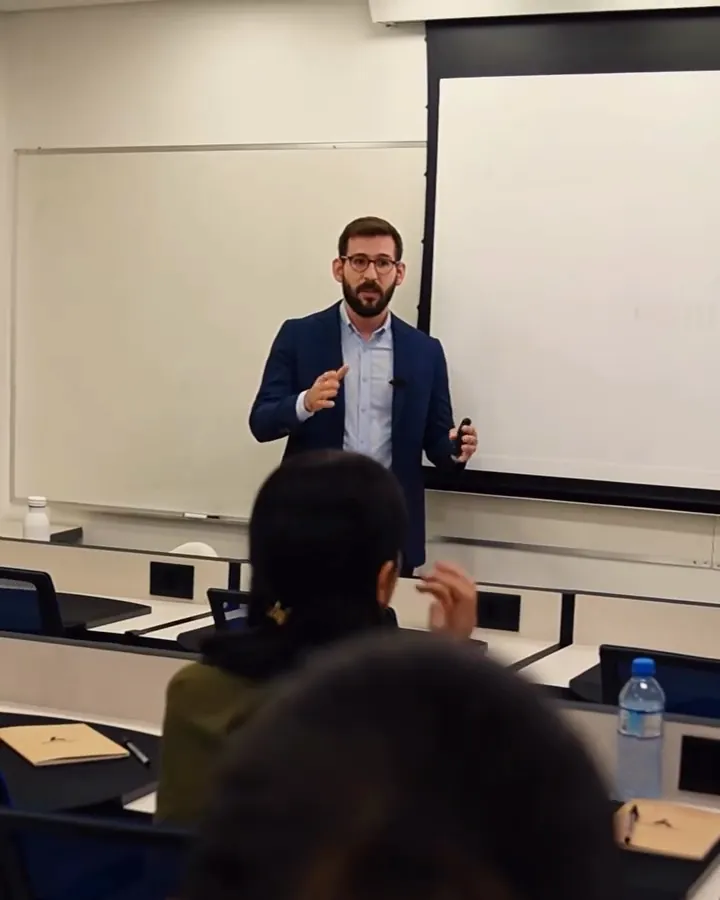 Dr. Eduardo Figueiredo dando aula para a turma, de pé diante da tela