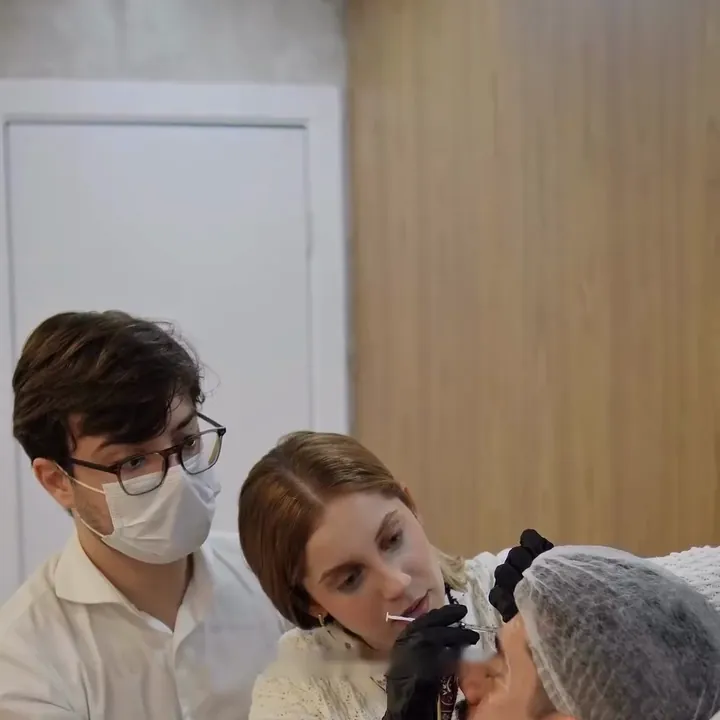 Aluna aplica no paciente modelo, com o Dr. Caíque Dias ao lado